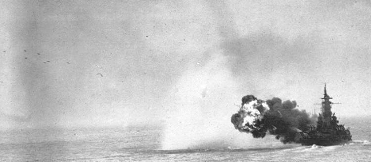 Battleship Massachusetts firing a full main battery salvo at Kamaishi, Iwate, Japan, 9 Aug 1945; note projectiles in flight at upper left