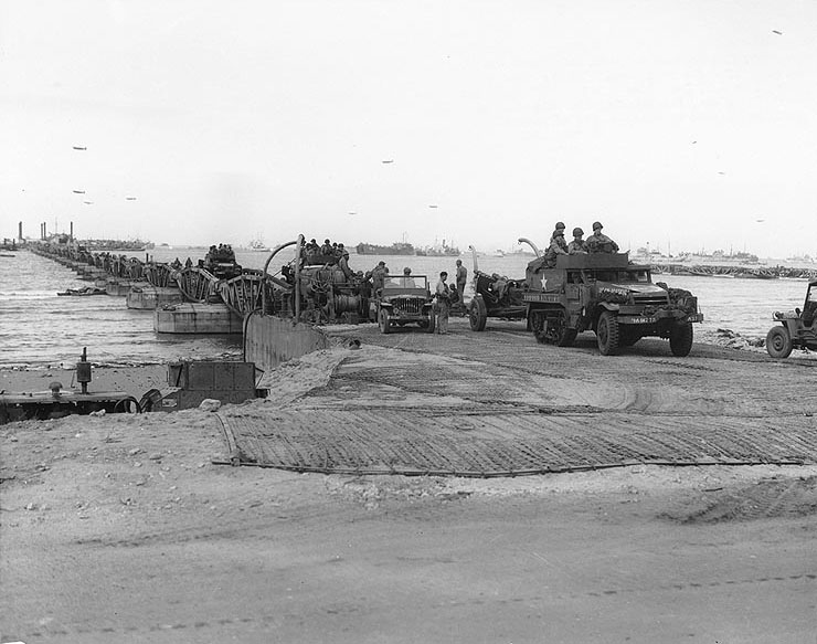 US Army vehicles came ashore on one of the floating causeways of the Mulberry artificial harbor off Omaha Beach, Normandy, 16 Jun 1944