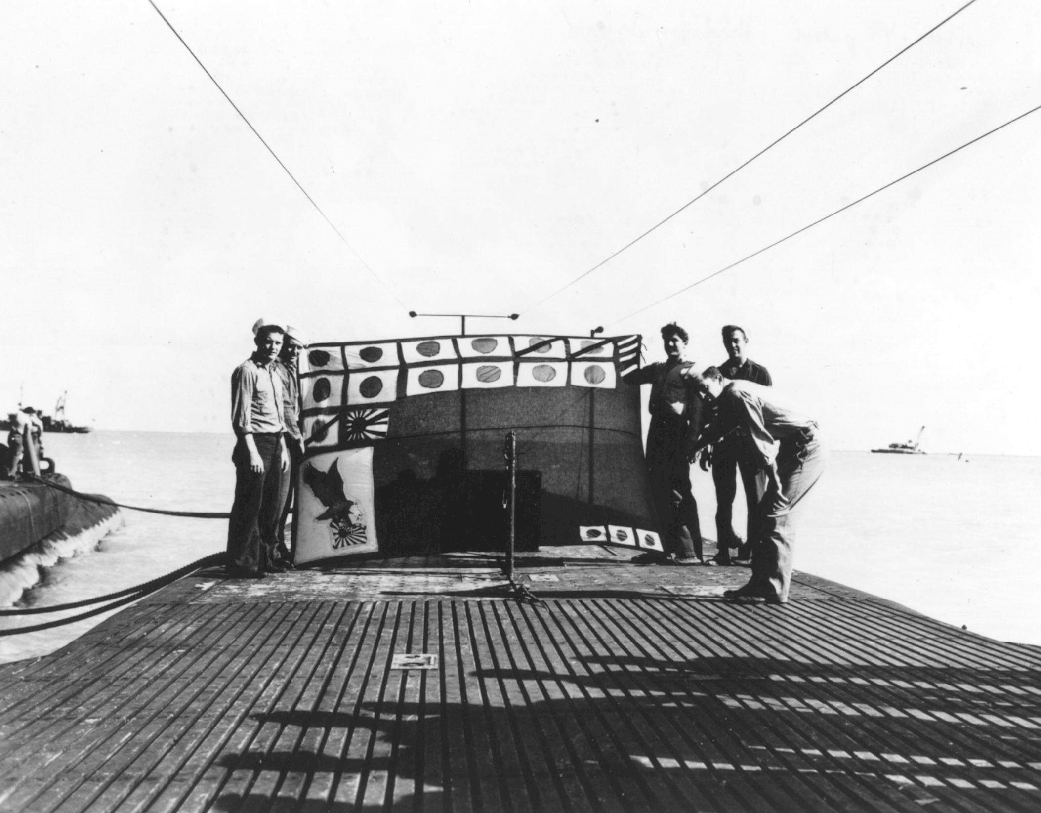 Crew of USS Snook holding up the submarine's scorecard, Midway, 7 Dec 1943