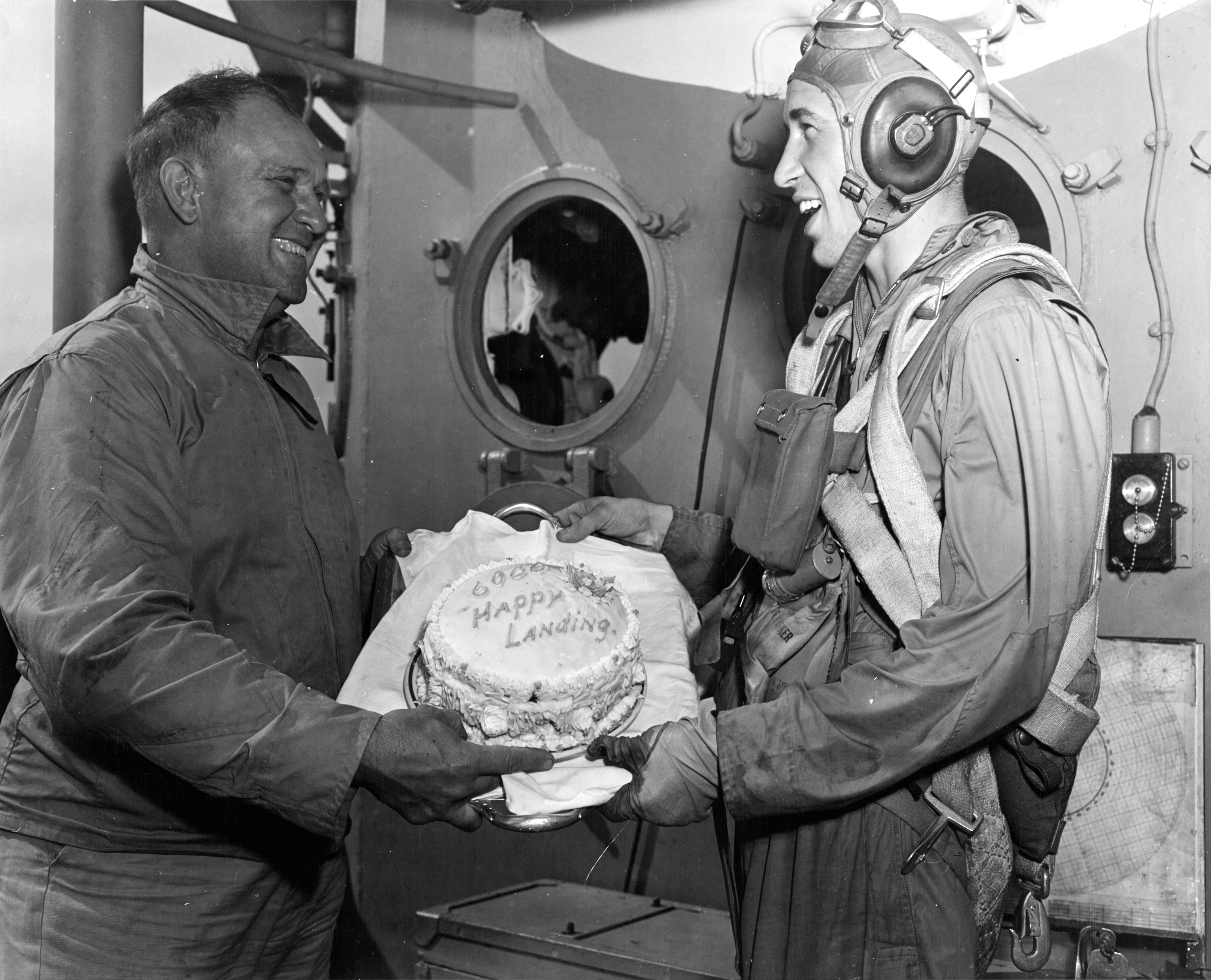 Captain Dixie Kiefer of USS Ticonderoga presenting VT-80 pilot Clyde Grow a cake for making the 6,000th landing on the carrier ('trap'), late 1944