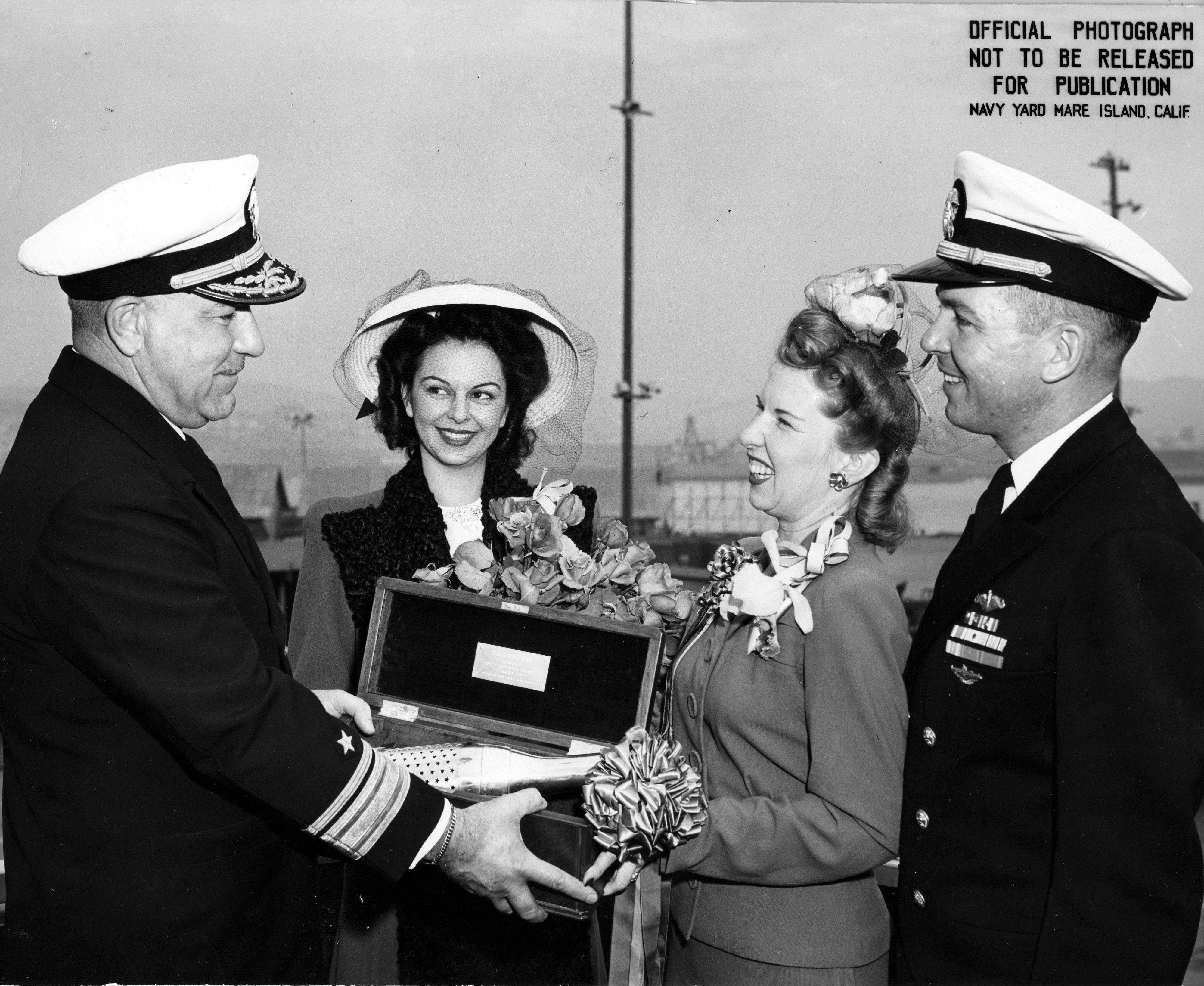 RAdm Mahlon Tisdale presenting champagne bottle to Mrs Davenport to christen Trepang, Mare Island Naval Shipyard, California, United States, 23 Mar 1944; Mrs Garvey and Cmdr Roy Davenport also present