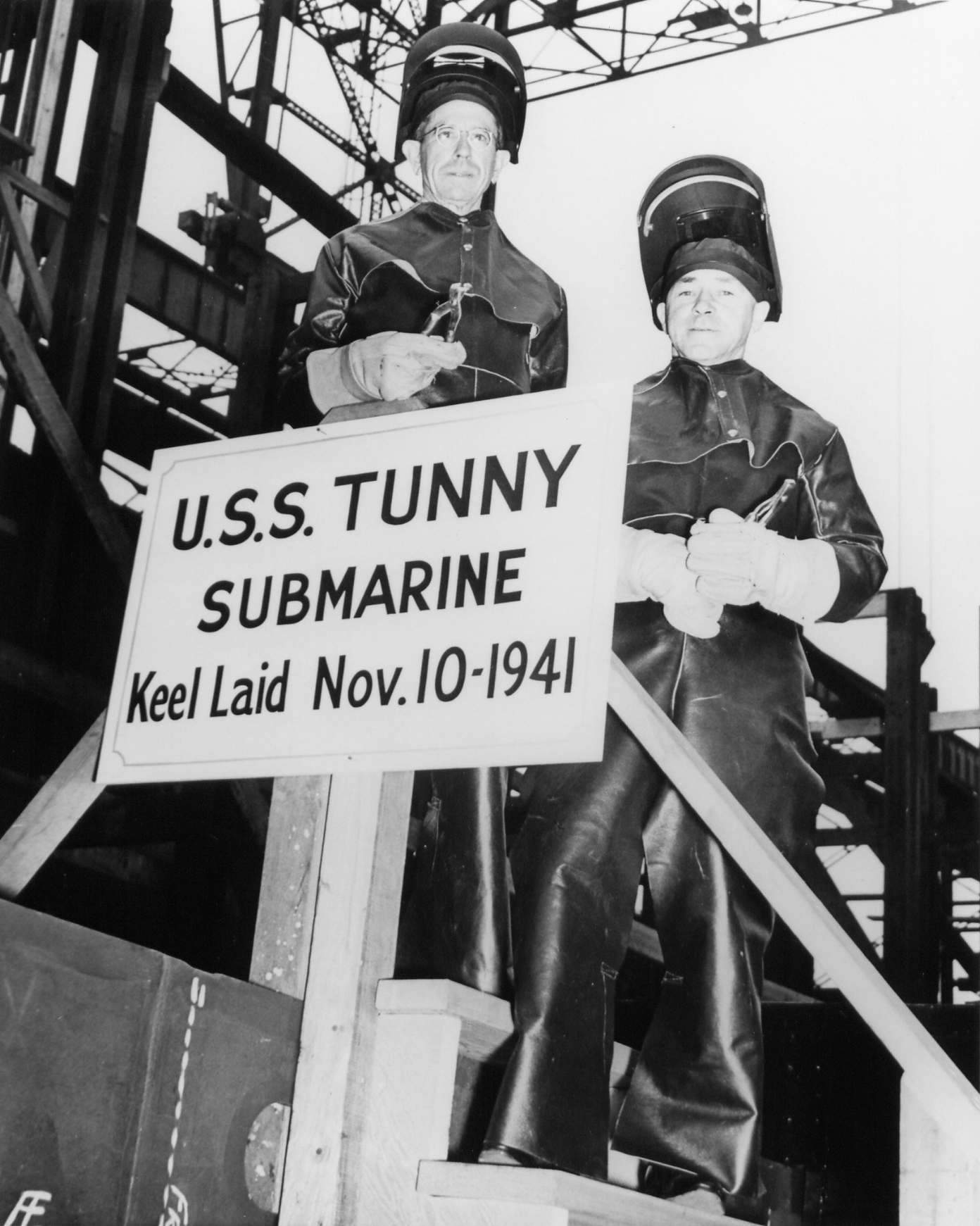 W. N. Simons and Robert F. Cooke, honorary keel layers of submarine Tunny, posing with the sign at Mare Island Naval Shipyard, California, United States, 10 Nov 1941