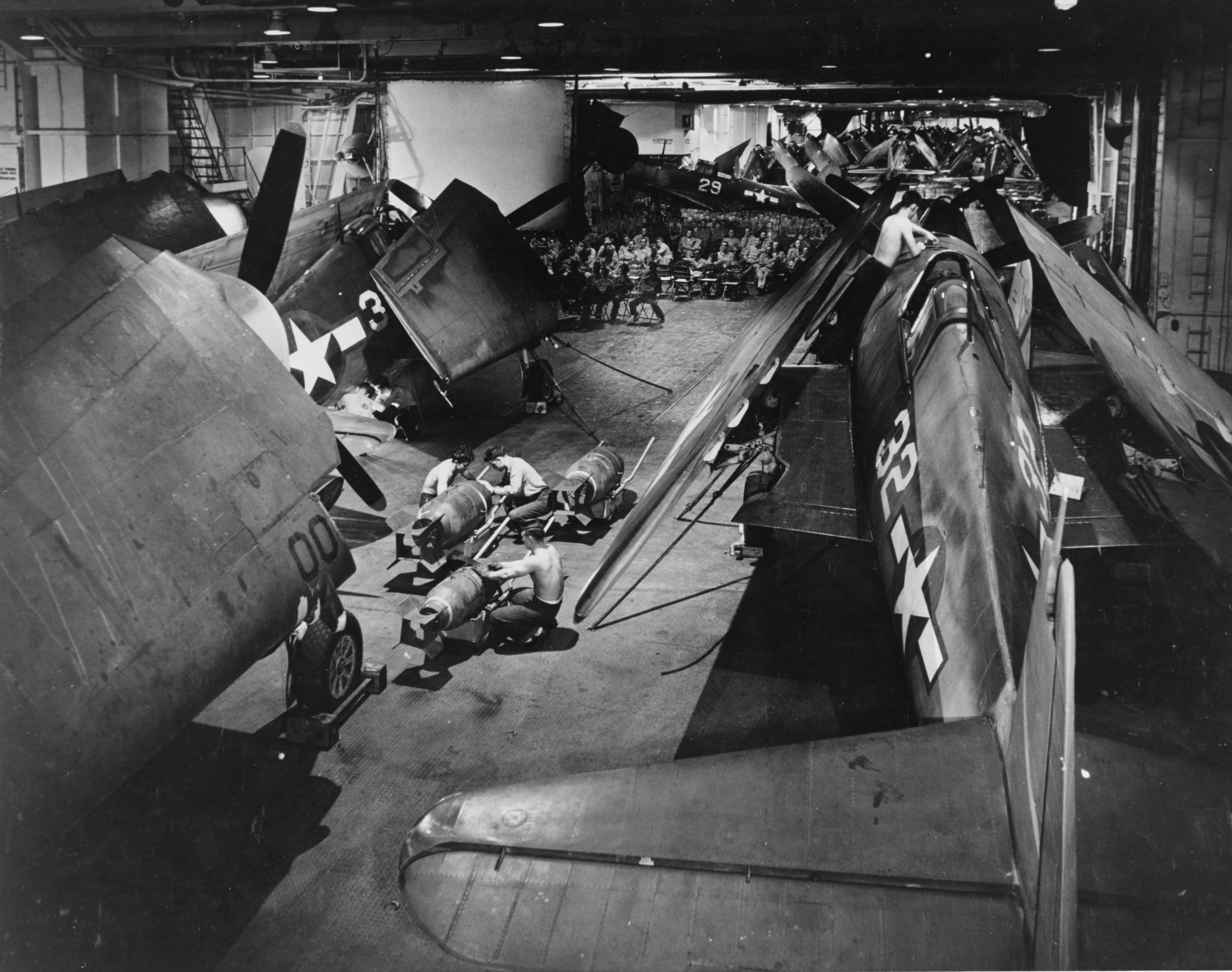 Ordnancemen working in USS Yorktown's hangar deck amidst F6F-3 Hellcat fighters, circa Oct-Dec 1943
