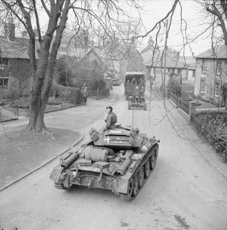 Covenanter tanks and towed artillery passing through a village during Exercise Spartan, Britain, 6 Mar 1943