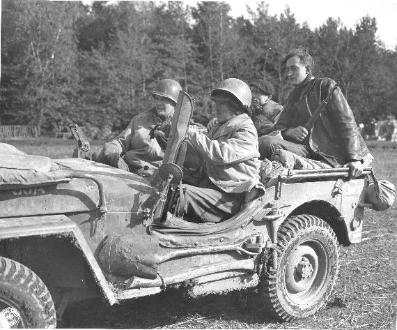Two Japanese-American soldiers of the US 442nd Regimental Combat Team in a jeep, accompanied by French guides, Chambois Sector, France, Oct 1944