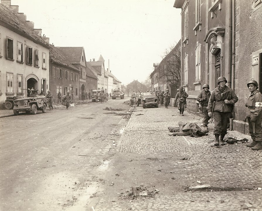 US soldiers in a recently captured town, 9 Dec 1944; note fallen US soldier