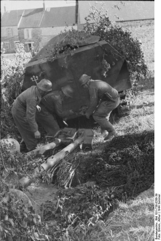German soldiers preparing to attach an anti-tank gun to the hitch of a SdKfz. 251 halftrack vehicle, France, 21 Jun 1944