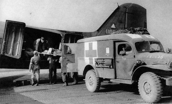 A patient being passed between C-47 Skytrain aircraft and Dodge WC54 ambulance, 1944-1945