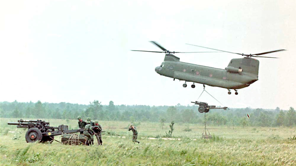 American troops taking delivery of a M101 105mm howitzer with ammunition pallet while a CH-47 Chinook helicopter landed another, Vietnam, 1968