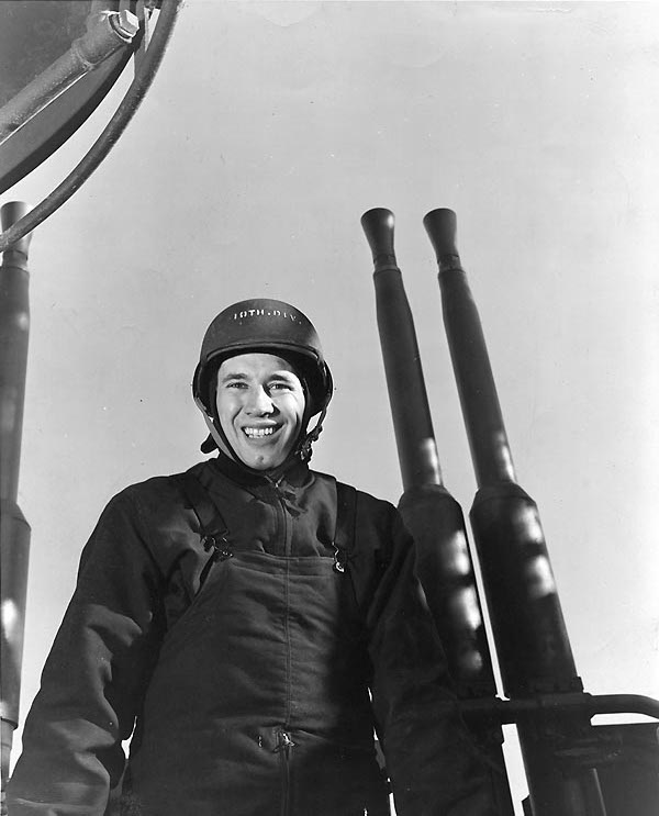 Bob Feller posing before a 40mm Bofors quad mount aboard a ship, possibly USS Alabama, 3 May 1943