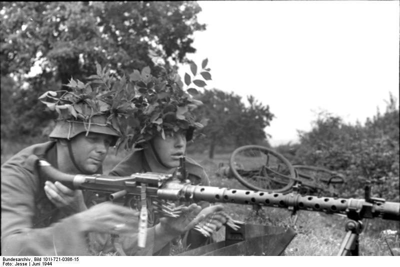 Two German soldiers with camouflaged helmets with a MG34 machine gun, France, Jun 1944