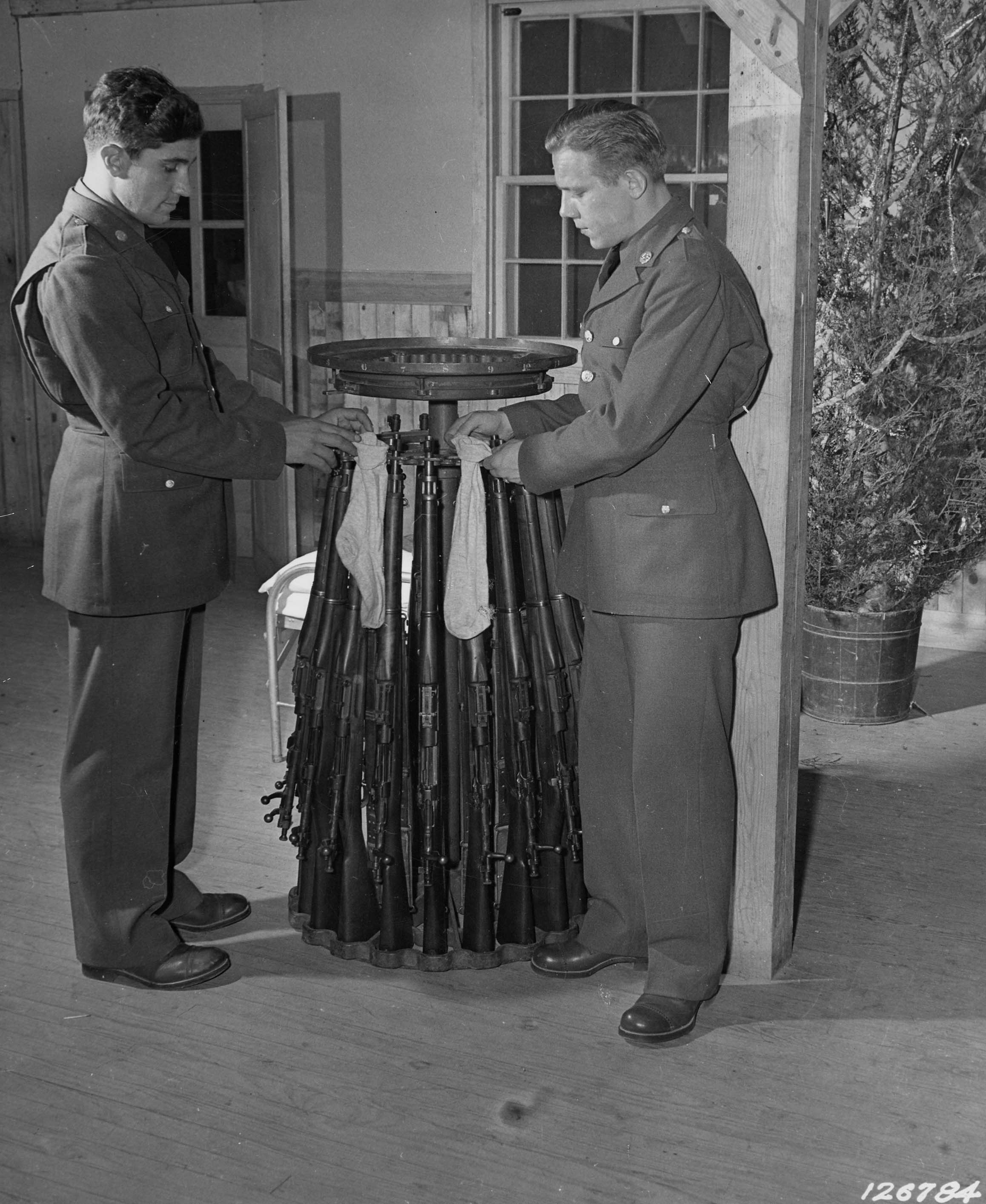 US Army Privates Kotula and Queen hanging stockings on Springfield M1903 rifles for the Christmas season, Camp Lee, Virginia, United States, Dec 1941